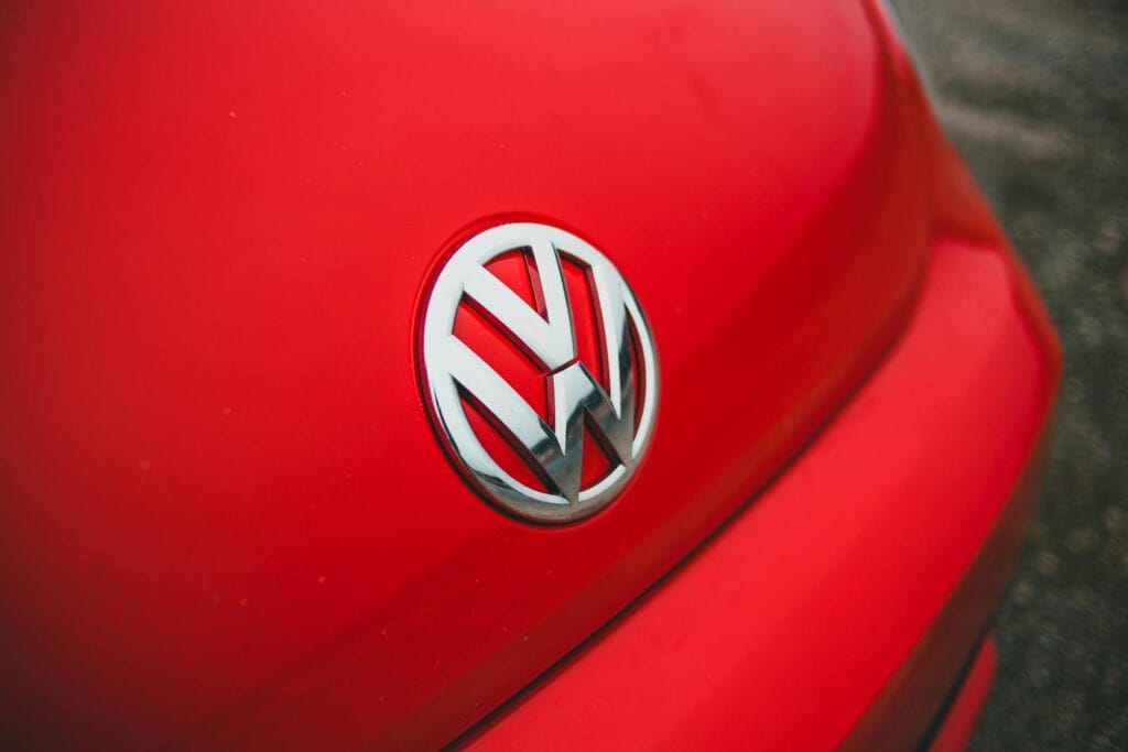 From above bright bonnet of contemporary red automobile with silver logotype parked on asphalt road on street of city